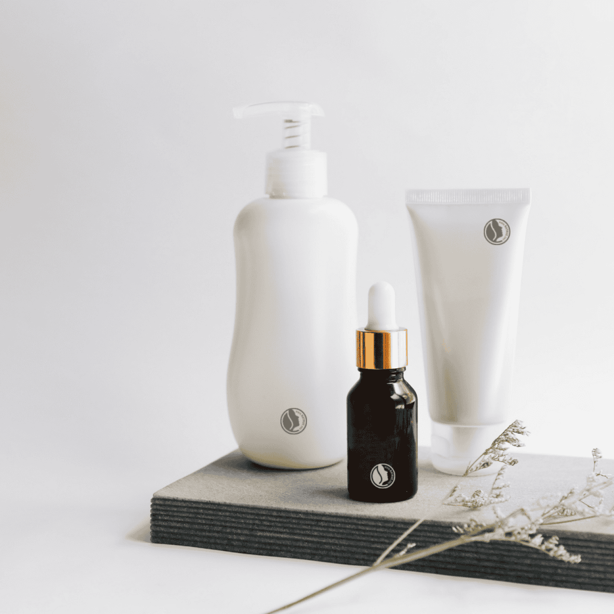 A bottle of oil, a bottle of lotion and a tube of cream.