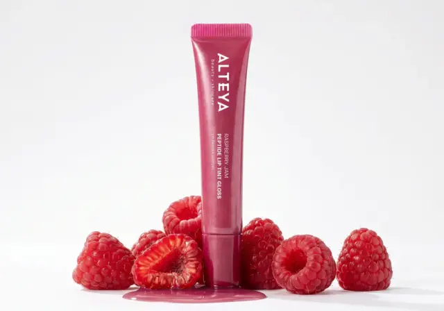 Гланц за устни с пептиди RASPBERRY JAM Alteya Organics, поставен сред свежи малини, за натурален и привлекателен вид.